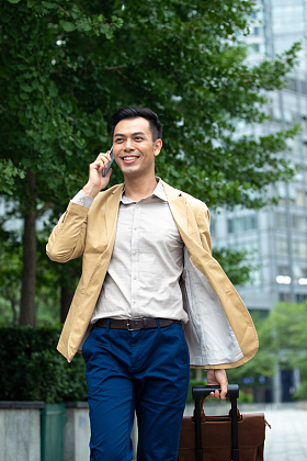 户外拉着行李打电话的商务男子