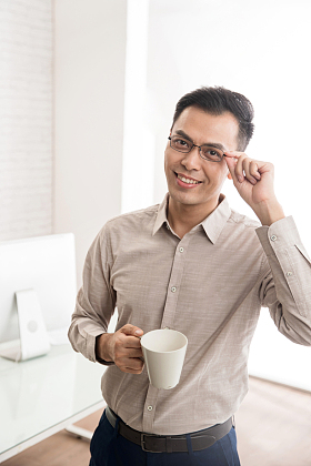拿着杯子手扶眼镜的商务男士